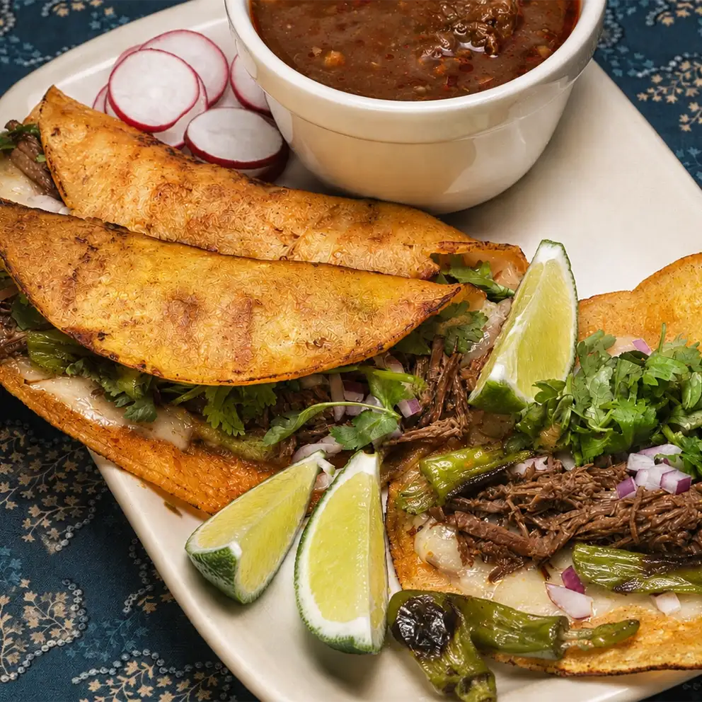 close up platter of tacos with lime and dipping sauce