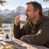 man sitting at wooden bench outdoors sipping accomplice bone broth from mug
