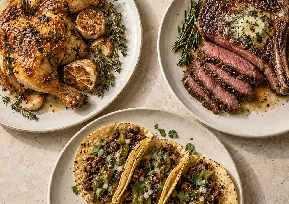 three plated meals of chicken, steak and tacos on table