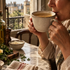 woman sipping chicken bone broth in a mug at her kitchen table by the window in the morning